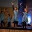 Dancers in blue dresses performing an uplifting routine at RDM's Castle Rock spring performance, celebrating worship through movement.